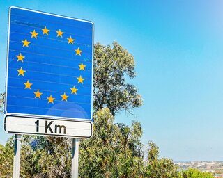 Ein Straßenzeichen zeigt die europäische Flagge und kündigt an, dass die EU-Grenze in einem Kilometer erreicht wird.