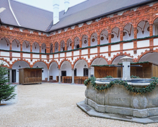 Der Innenhof zeigt eine reizvolle Architektur mit roten Steinen und weißen Wänden, verziert mit Pflanzen und einem zentralen Brunnen.